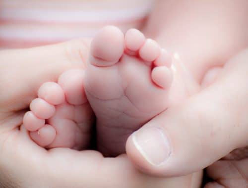 mãos segurando um pé de bebê
