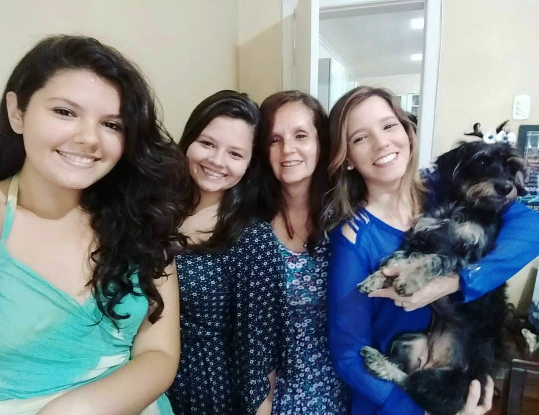 4 mulheres juntas sorrindo, uma delas segura o cachorro