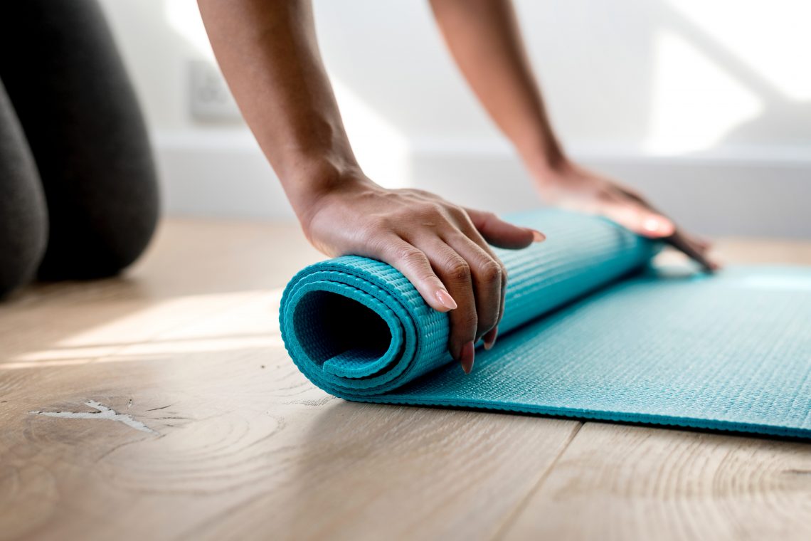 mão enrolando um tapete de yoga