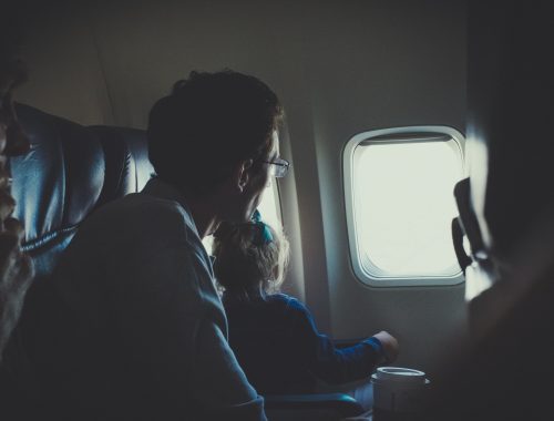 homem com uma criança pequena olhando a janela de um avião