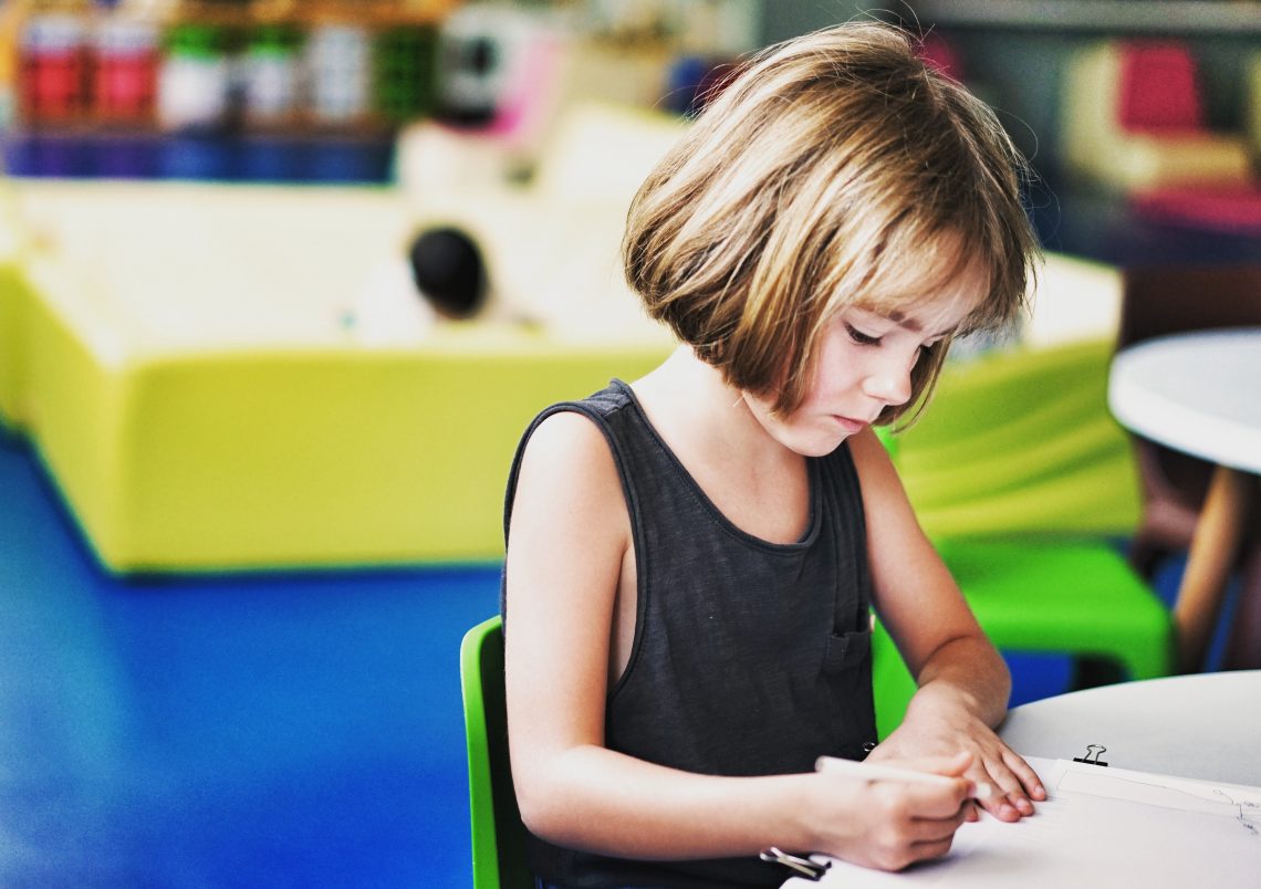menina escrevendo em um ambiente escolar