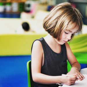 menina escrevendo em um ambiente escolar