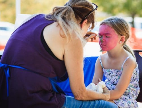 mãe pintando o rosto da filha de rosa