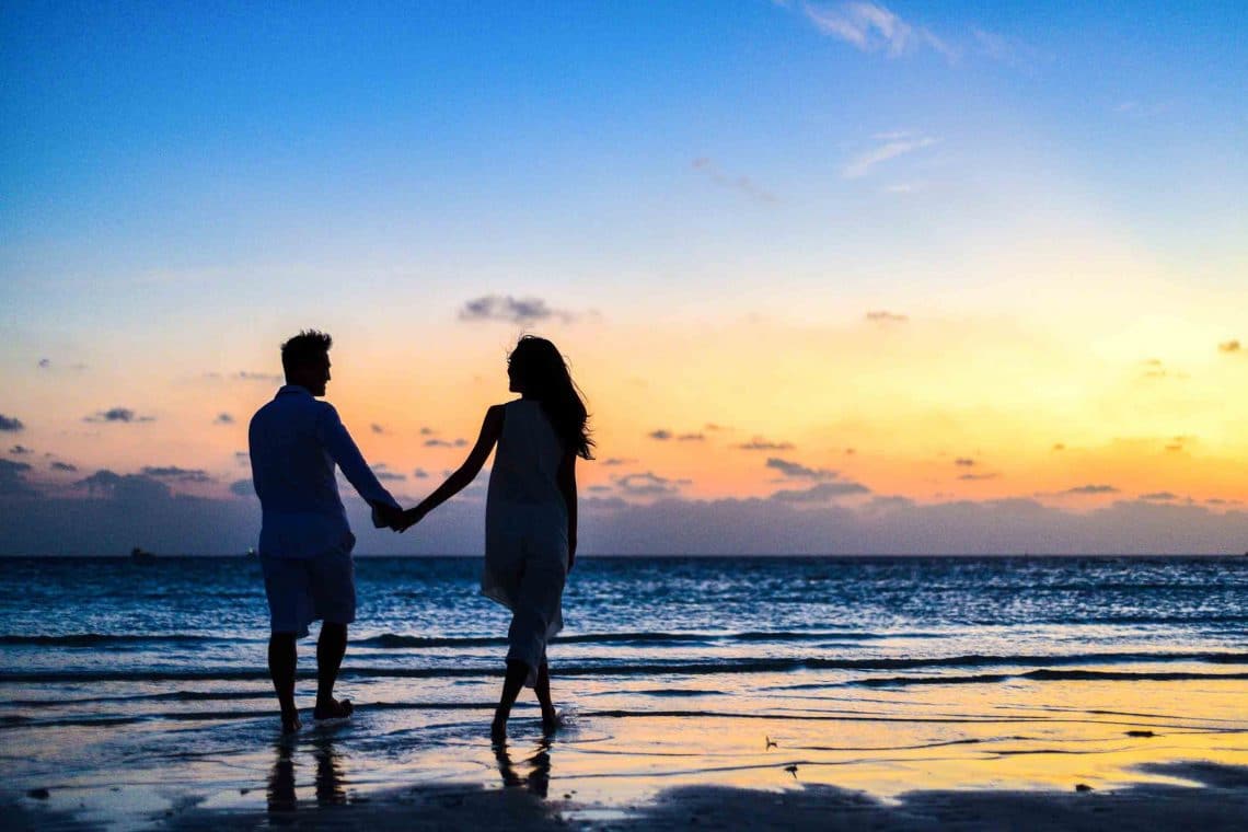 casal andando de mãos dadas na praia