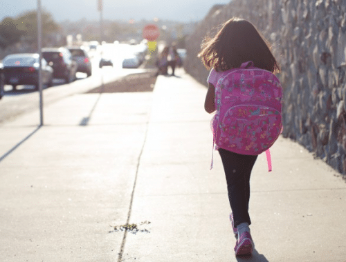 menina com mochila andando sozinha para escola