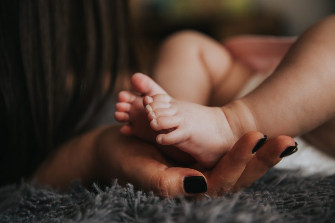 mão de mulher segurando o pé de um bebê