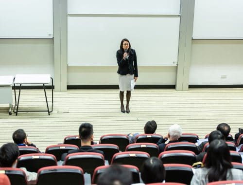 mulher ensinando na frente de um publico