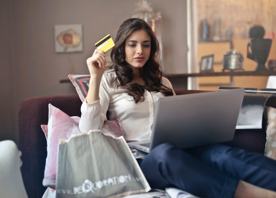 mulher segurando um cartão de credito e fazendo compras pela internet