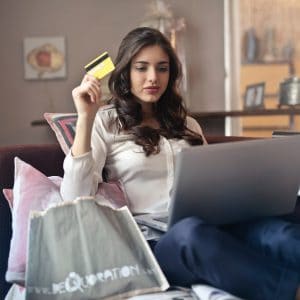 mulher segurando um cartão de credito e fazendo compras pela internet