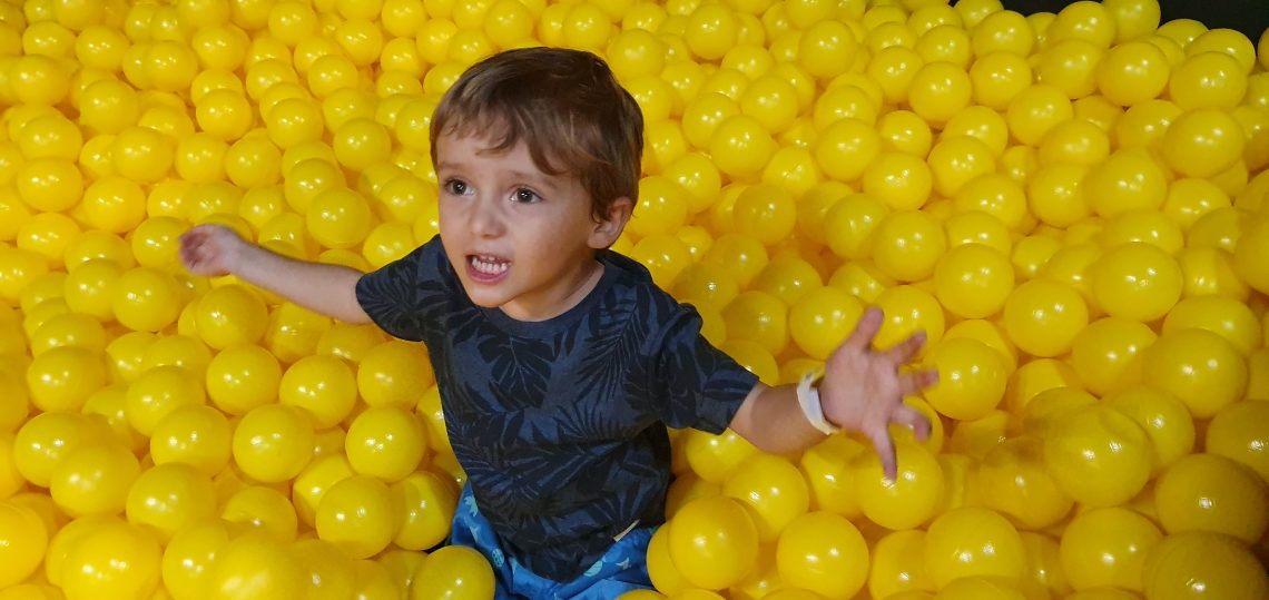 criança em uma piscina de bolinha amarela