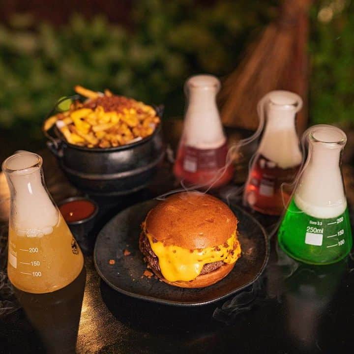 mesa com hambúrguer, caldeirão de batata frita e drinks com estética mística em restaurante harry potter beco hexagonal