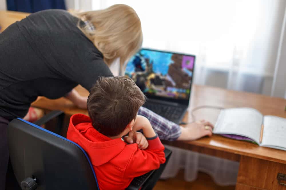 mãe mexendo no computador junto do seu filho descobrindo o que é roblox e seus controles parentais